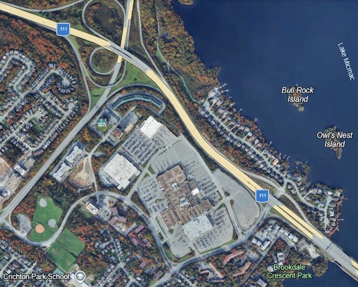 Capture d'écran d'une photo satellite de Google Earth qui montre un centre commercial entouré de grands espaces asphaltés, près d'une autoroute et d'un lac.