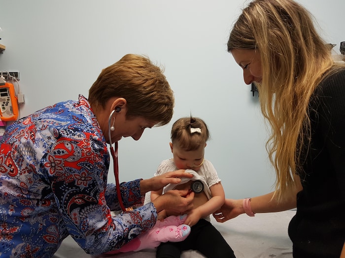 Une médecin ausculte le coeur d'une fillette en compagnie de sa maman.