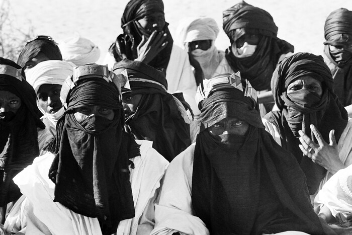 Une photographie d'archive en noir et blanc illustrant des hommes touaregs portant leurs chèches, foulards traditionnels.