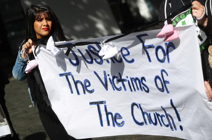 Une manifestante tient une bannière où on peut lire : « Justice pour les victimes de l'Église » à Dublin, en Irlande.