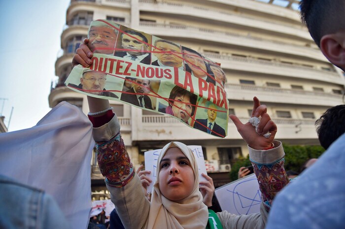Une jeune Algérienne brandit une pancarte dans la rue.