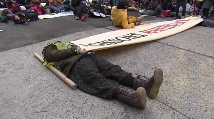 Un manifestant est couché sur le dos sur l'asphalte afin de simuler la mort pendant une marche pour le climat.