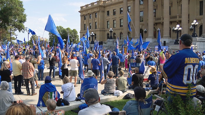 Des personnes portant des symboles de l'Alberta devant l'Assemblée législative albertaine.