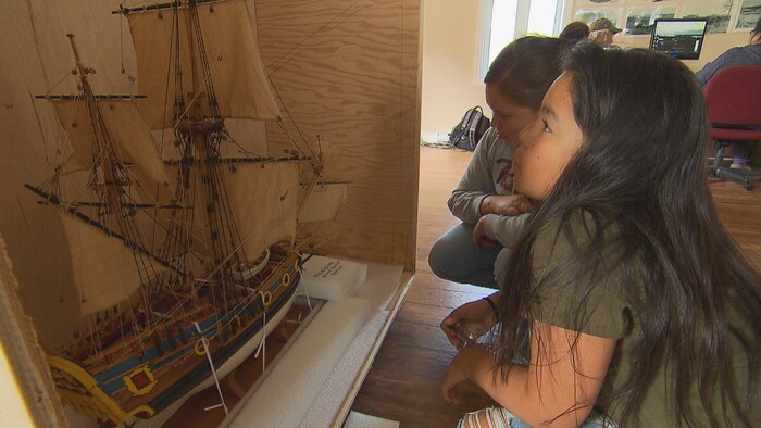 Deux jeunes filles regardent le modèle réduit du navire. 
