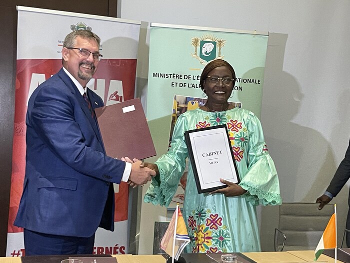 Un document officiel à la main, Mariatou Koné pose pour une photo en offrant une poignée de main à Bill Hogan.