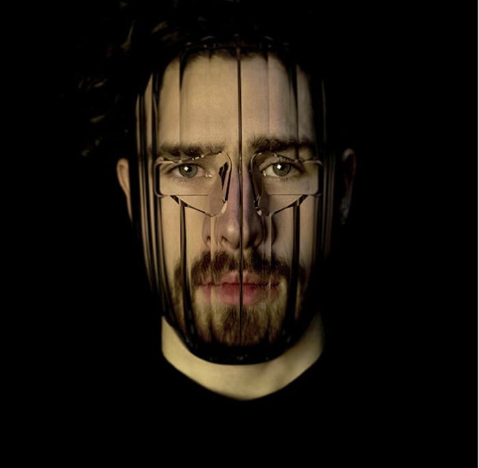 Un homme porte un masque en plastique transparent qui déforme les traits de son visage. 