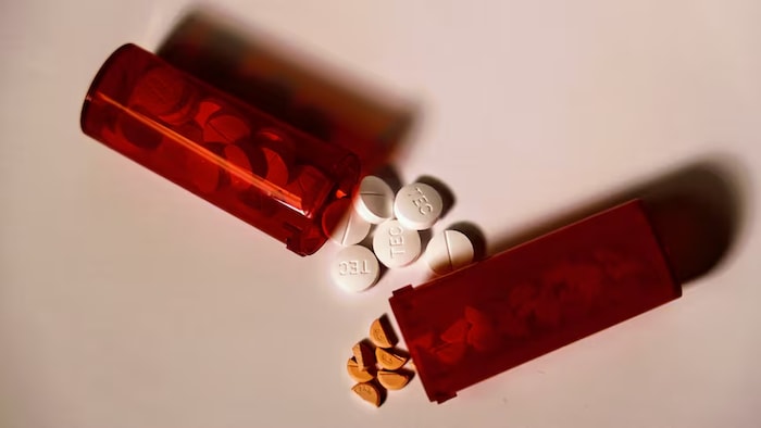 Deux contenants de médicaments et des comprimés sont posés sur une surface.