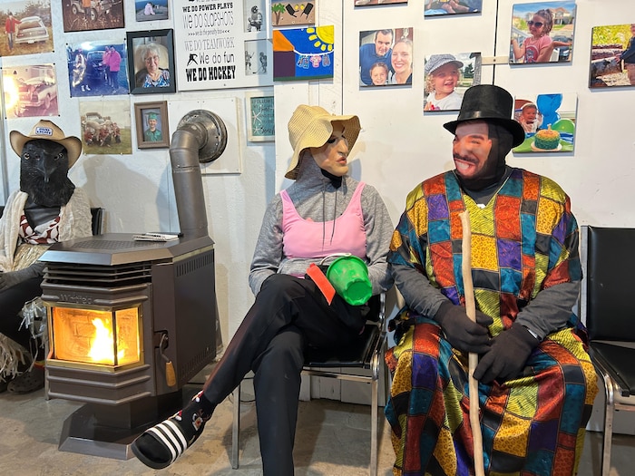 Trois personnes costumées sont assises autour du vieux poêle.