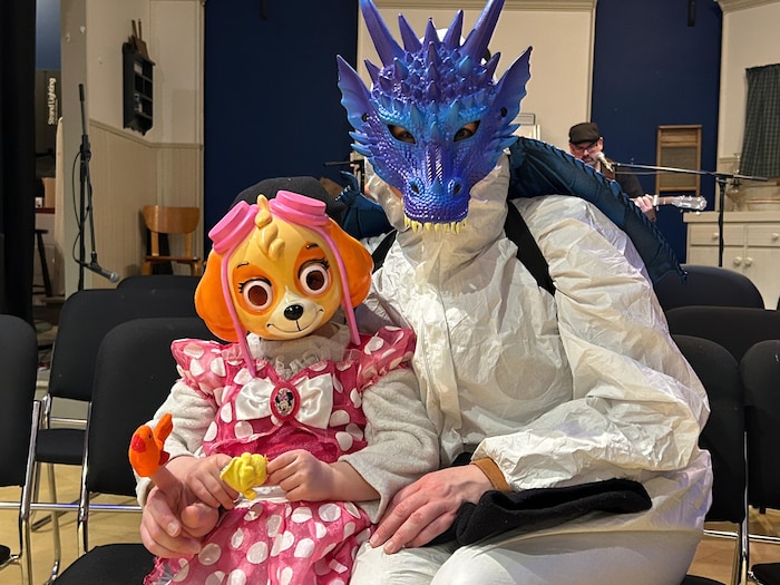 Un adulte et un enfant posent ensemble, assis. Ils portent des masques et on ne les reconnaît pas.