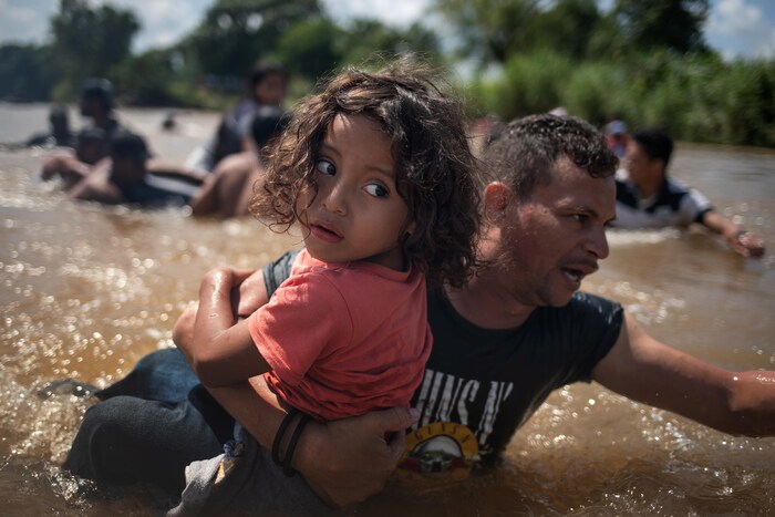 Un homme d’une caravane de migrants d'Amérique centrale en route vers les États-Unis, porte une jeune fille en traversant le fleuve Suchiate jusqu'au Mexique.