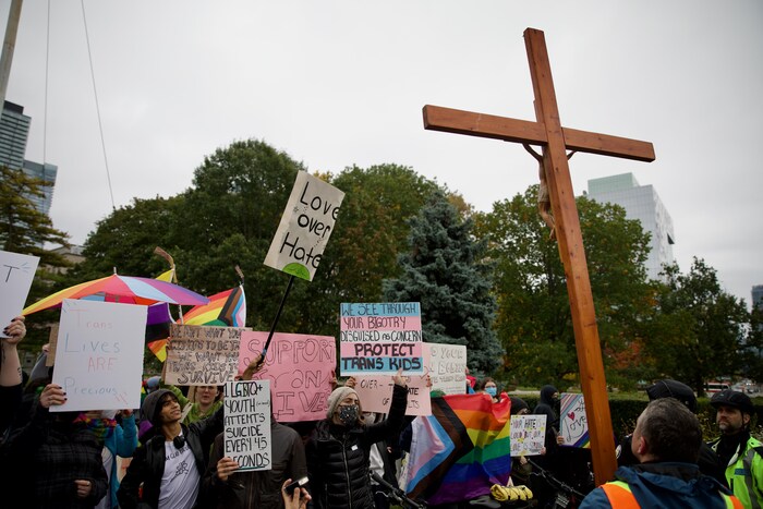 Défenseurs des droits de la communauté LGBTQ+ devant un crucifix.