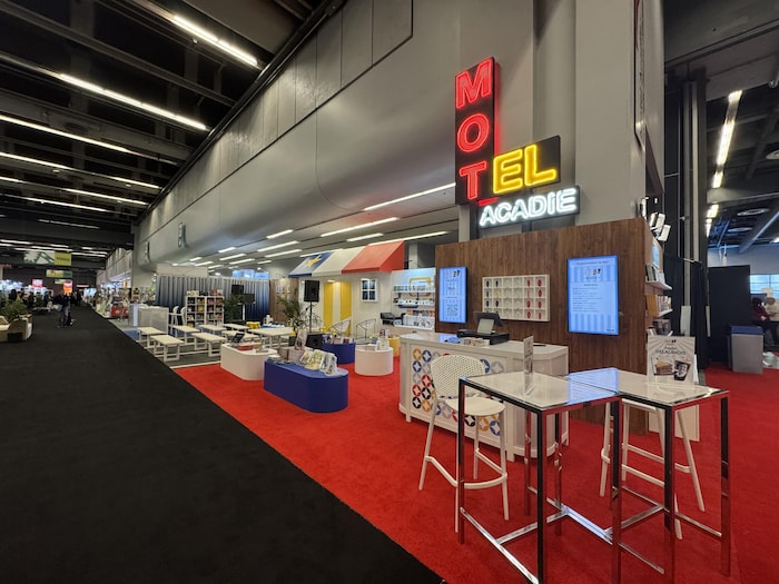 Des tables et des &eacute;talages sur un tapis rouge, sous une enseigne de motel lumineuse, avant l'ouverture du salon.