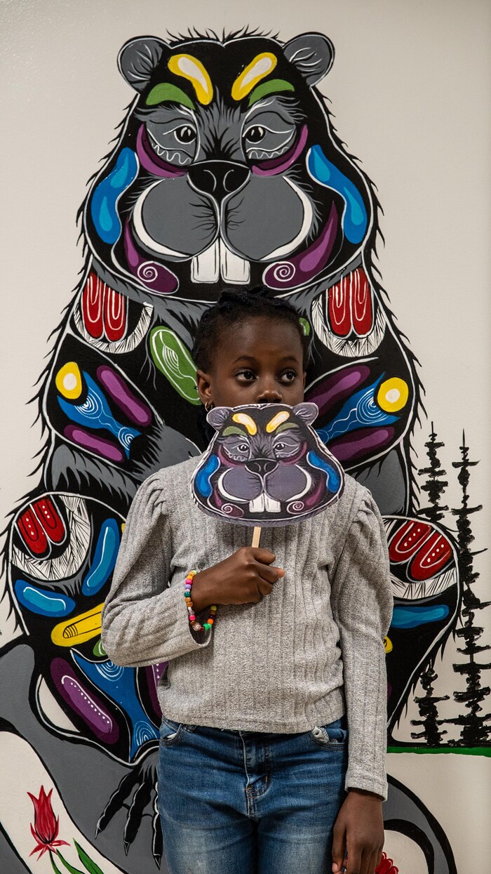 Une enfant de l’École Jeanne-Sauvé à Sudbury pose devant la murale autochtone de l’école. 
