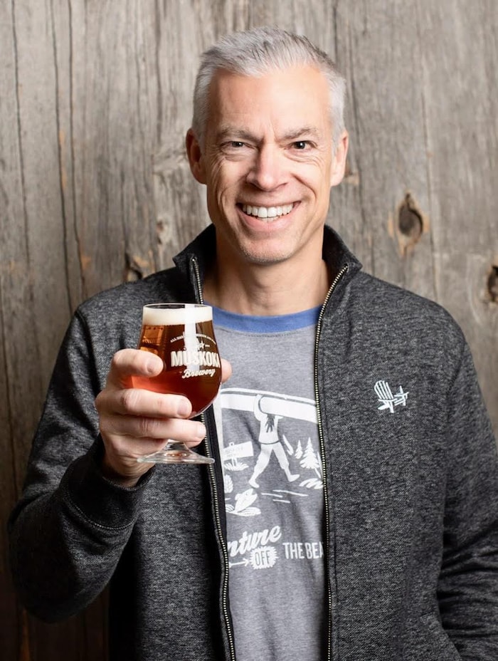 Todd Lewin qui tient un verre rempli de bière.