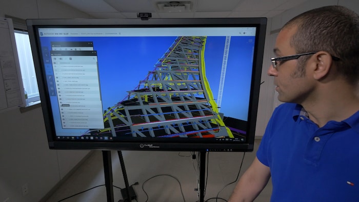 On voit M. Nafa, de profil, qui regarde l'écran où est projetée la modélisation virtuelle de la tour du stade.
