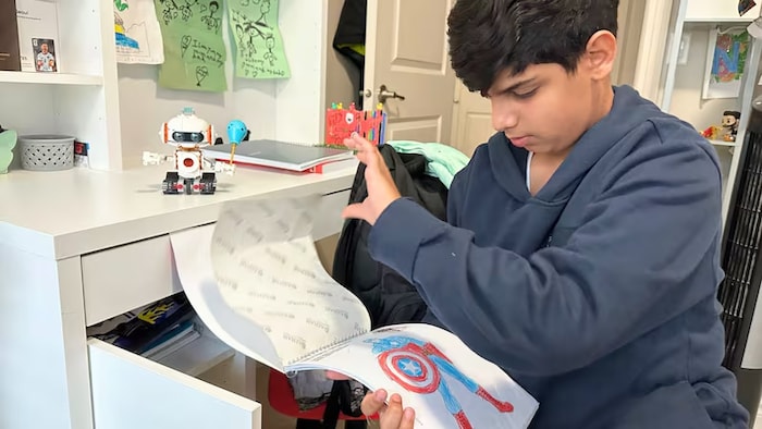 Un jeune garçon tient un cahier entre ses mains.