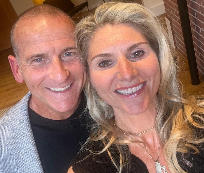 Un couple sourit devant l'objectif d'une caméra.