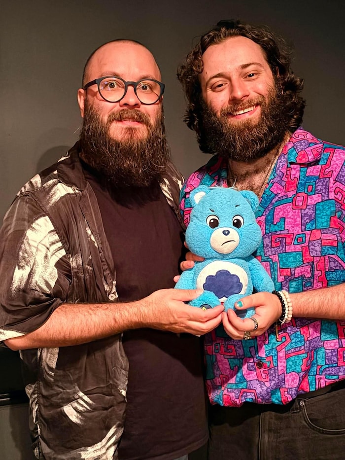 Pierre Castonguay et Nicolas Chouinard font la pose devant la caméra en tenant un nounours dans leurs mains.