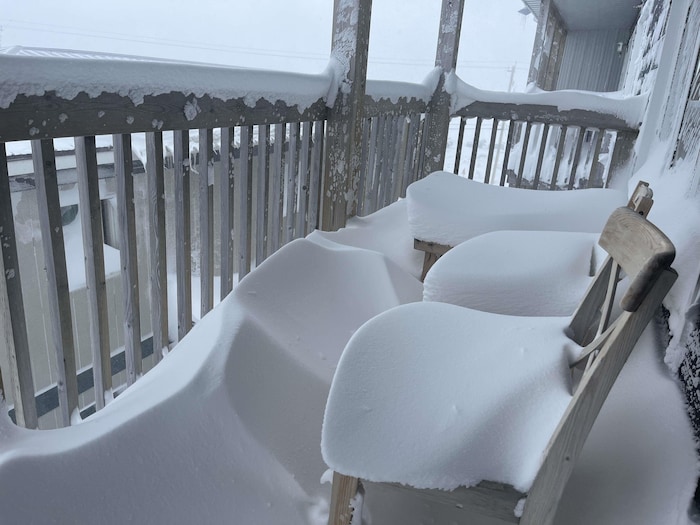 Deux chaises couvertes de neige sur le balcon d'une résidence à Iqaluit, au Nunavut, lors d'un blizzard le 15 mai 2025.