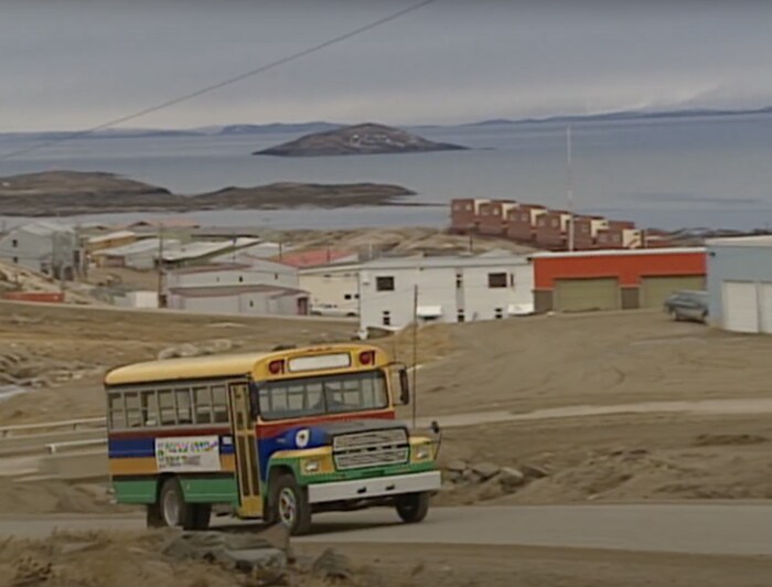 Un autobus multicolore roule sur une route d'Iqaluit, au Nunavut, au début des années 2000.