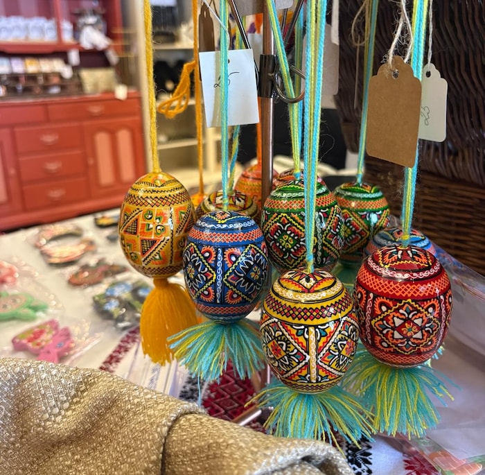 Neuf œufs peints en rouge, bleu ou jaune, suspendu à de petites cordes colorées, et ornés d'une étiquette pour la vente.