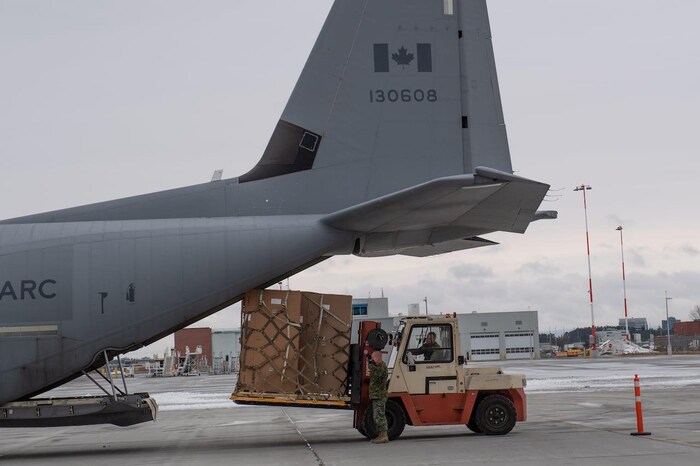 Canadian Armed Forces traffic technicians load special freezers onto aircraft pallets.