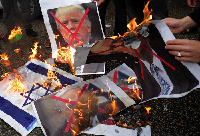 Des manifestants brûlent une photo de Donald Trump de même que des drapeaux américains et israéliens.