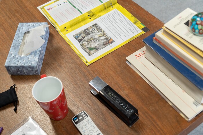 Une table sur laquelle sont posés une agrafeuse, une tasse, une boîte de papier-mouchoirs, des manuels et des cahiers scolaires.