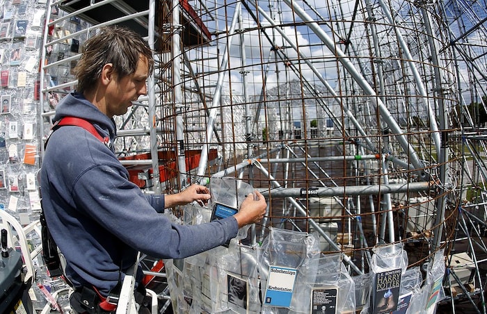 Un ouvrier fixe les livres plastifiés sur la structure métallique du « Parthénon des livres »