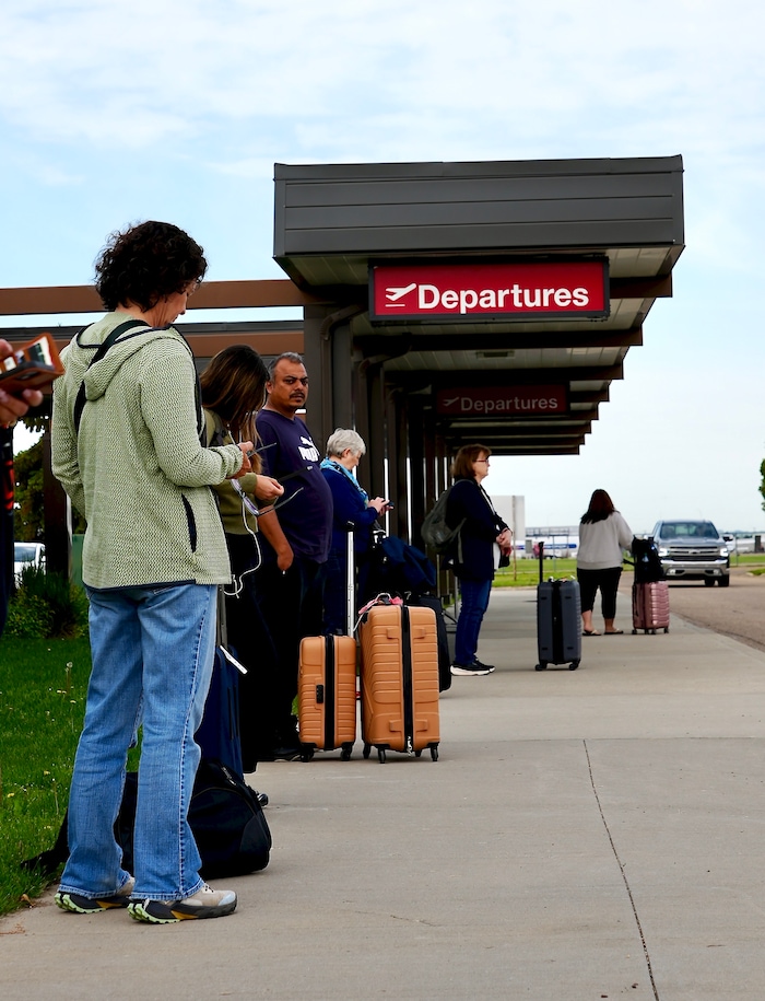 Des passagers attendent qu'une navette vienne les chercher après leur arrivée à l'aéroport régional de Medicine Hat, le 16 juin 2026.