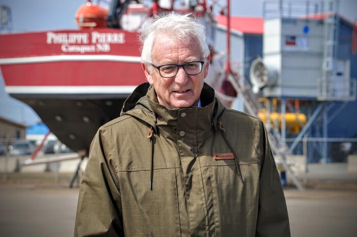 Jean Lanteigne, debout devant un gros bateau de pêche.