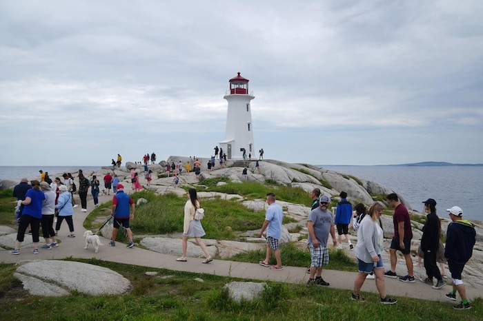 Tourists visit the lighthouse in Peggy's Cove, N.S., on Canada Day in 2022. Canada is struggling to get back into the top 10 most-visited countries by tourists.