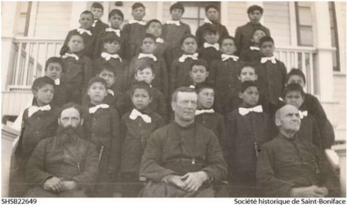 Le père Célien Gauthier (à g. au 1er rang) avec des élèves autochtones de l'école résidentielle de Sandy Bay dans les années 1930.
