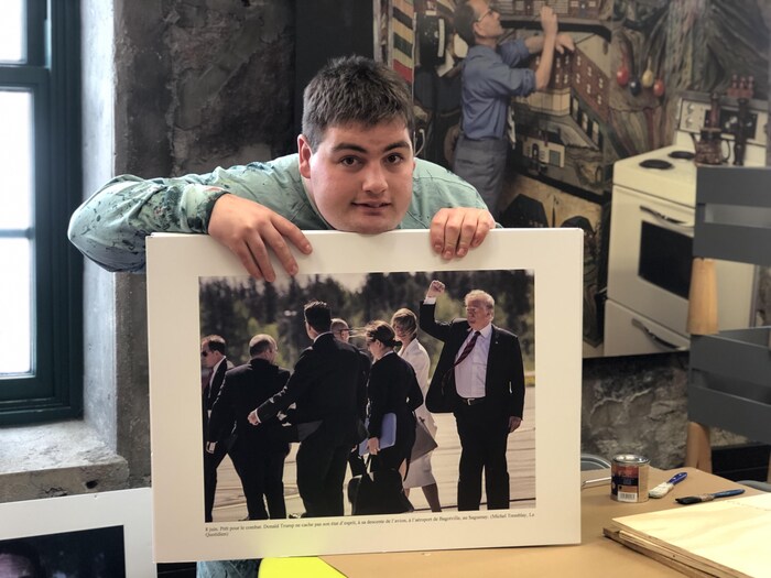 Un jeune homme tient une photo du Sommet du G7 dans ses mains.
