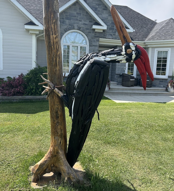 A giant sculpture of wooden pic-beast, in front of a house. he sculpts giant birds beach new