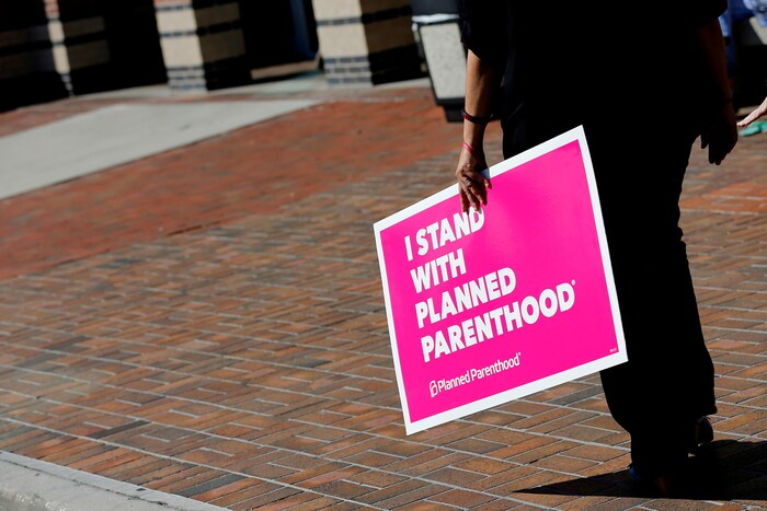 Une femme tient une pancarte indiquant : « Je soutiens Planned Parenthood », référant aux cliniques de planification familiale qui sont dans le viseur de l'administration Trump.