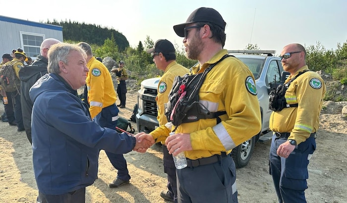Le ministre serre la main d'un homme en uniforme jaune.