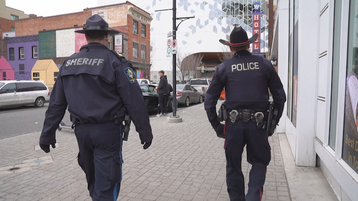 Un policier et un shérif marchent de dos.