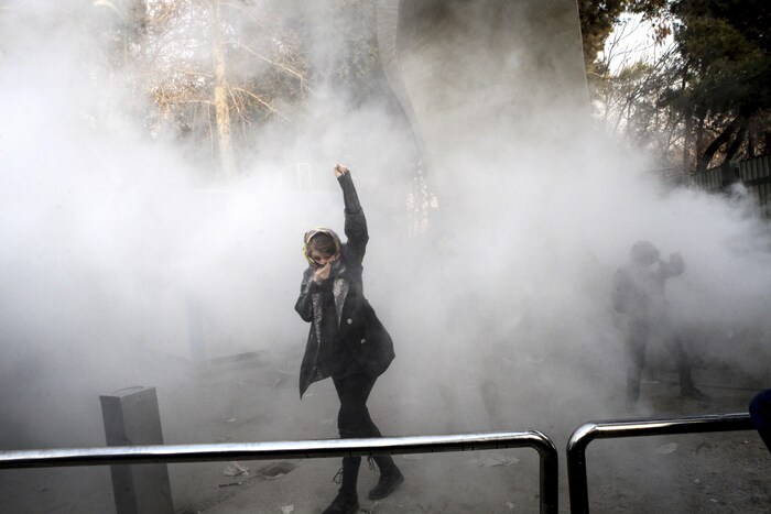 Une manifestante brandit le poing dans un nuage de gaz lacrymogène sur le campus de l'Université de Téhéran.