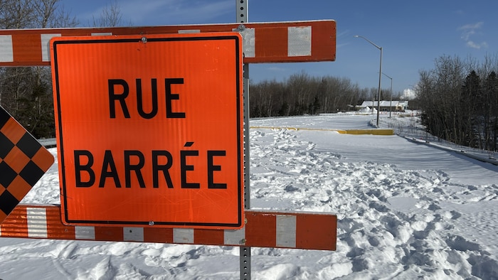 Une affiche indiquant une rue barrée en hiver.