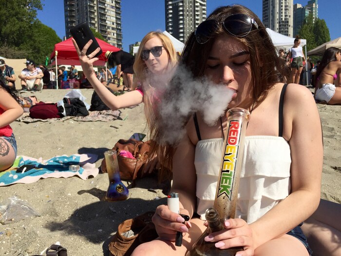 Une jeune femme fume de la marijuana sur la plage.