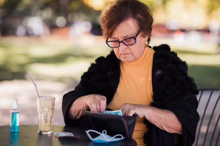 Una mujer buscando dinero en su cartera. El informe concluye que los ingresos medios de los ancianos indígenas y racializados son un 25% y un 32% inferiores, respectivamente, a los de los canadienses blancos.
