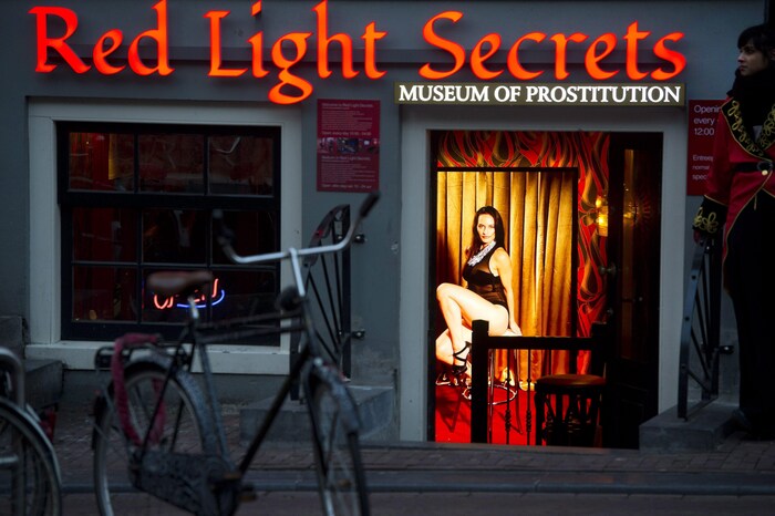 On voit une femme vêtue de lingerie noire offrir ses services sexuels dans une vitrine du Red Light District d'Amsterdam en 2014 