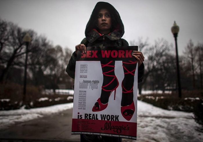 Une femme tient une affiche sur laquelle il est écrit, en anglais, que le travail sexuel est un vrai emploi, lors d'une manifestation devant la Cour suprême du Canada en 2013.