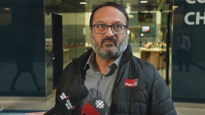 Un homme se tient debout devant des microphones de journalistes.