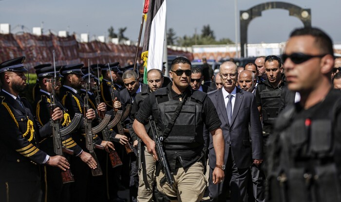 Un homme lourdement armé précède le premier ministre Hamdallah lorsqu'il passe devant une haie d'honneur formée de policiers du Hamas.