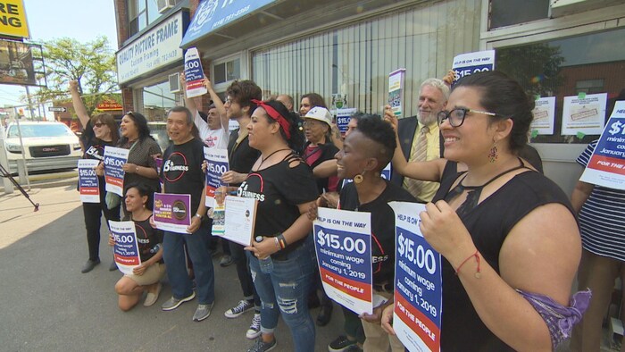 Des militants en faveur de l'augmentation du salaire minimum à 15 $ l'heure sont rassemblés dans la circonscription provinciale d'Eglinton-Lawrence à Toronto. 