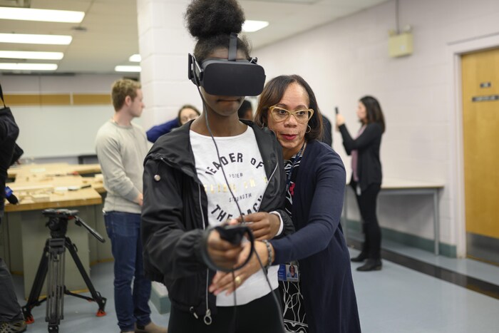 Une directrice d'école aide une adolescente portant un casque de réalité virtuelle.