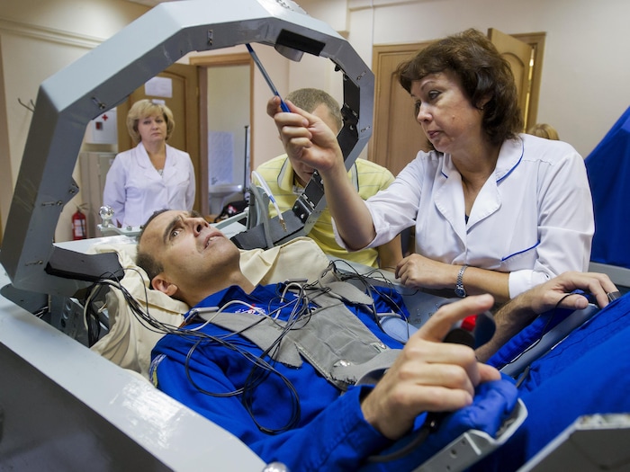 Un astronaute en habit bleu couché regarde vers le haut.