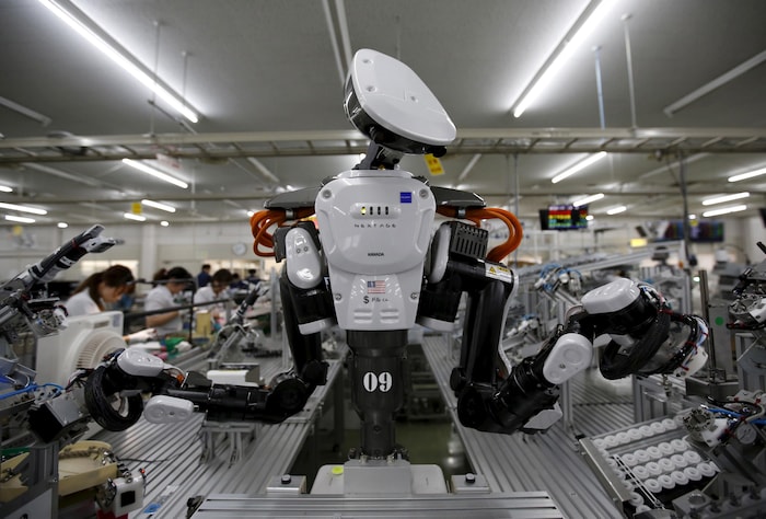 Un robot doté de deux bras et de ce qui ressemble à une tête, dans une manufacture.